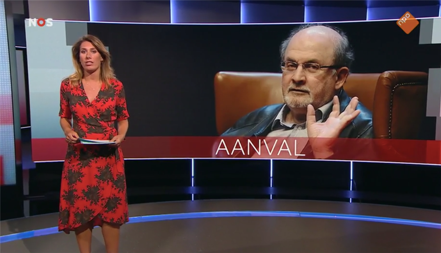 Beeld uit het NOS Journaal toont de nieuwslezer op de voorgrond, met op de achtergrond een portret van Rushdie, met daarbij de tekst ' AANVAL' .